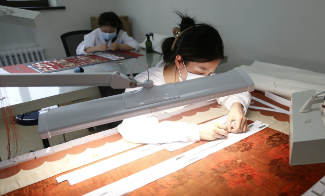“青春华章重走西北角”采访团探秘甘肃省博物馆：千年珍宝诉说丝路辉煌_fororder_修复人员正在对纸质文物进行修复