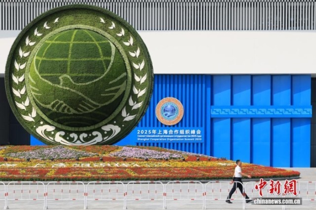 8月31日，天津，一名工作人员从2025年上海合作组织峰会主会场外的景观花坛旁经过。当日，2025年上海合作组织峰会在天津举行。<a target='_blank' href='/'><p  align=